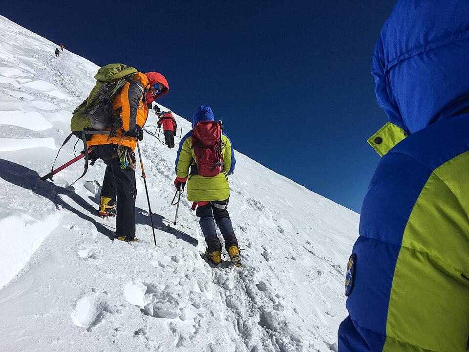 Climbers ascending the west peak of Mount Elbrus on a clear morning.