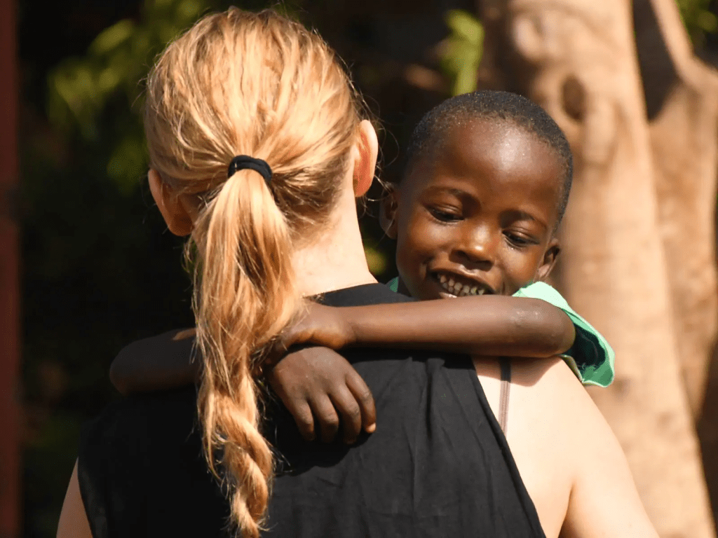A volunteer shares a warm embrace with a child supported by Zara Charity, reflecting the organization’s commitment to compassion and community care in Tanzania.