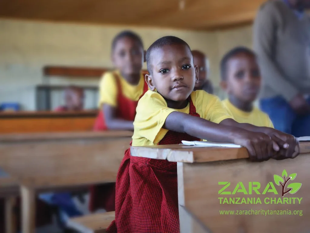 A young Tanzanian child in a classroom supported by Zara Charity, part of early education initiatives empowering local communities through sustainable tourism.