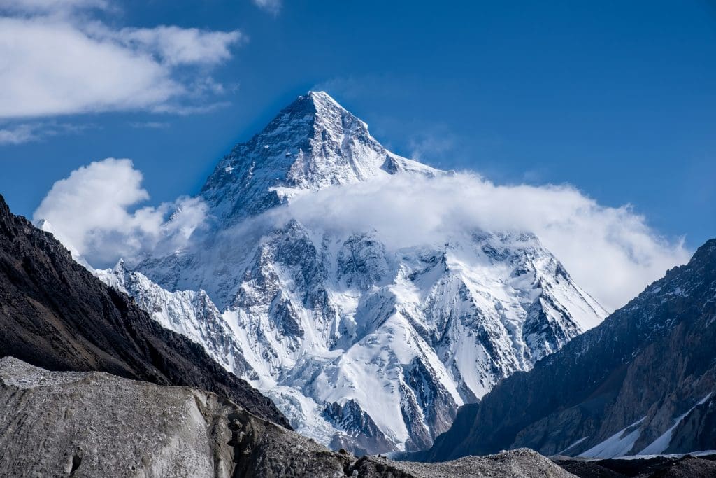 The summit of K2 emerging through blue skies and swirling mist