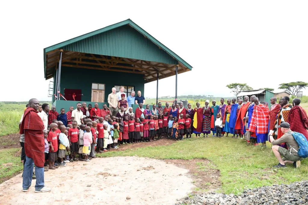 Community members, children, and volunteers gather outside the Maasai pre-school in Ngorongoro, a Zara Charity initiative supporting early childhood education in Tanzania.