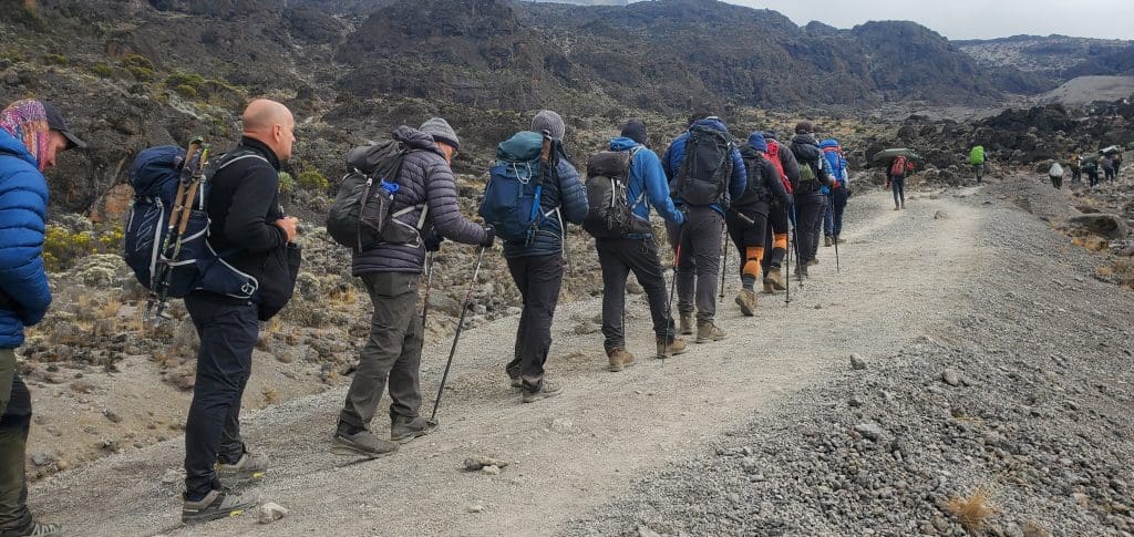 Group of trekkers hiking slowly through the rocky high-altitude zone of Mount Kilimanjaro, where reduced oxygen levels increase the risk of altitude sickness.