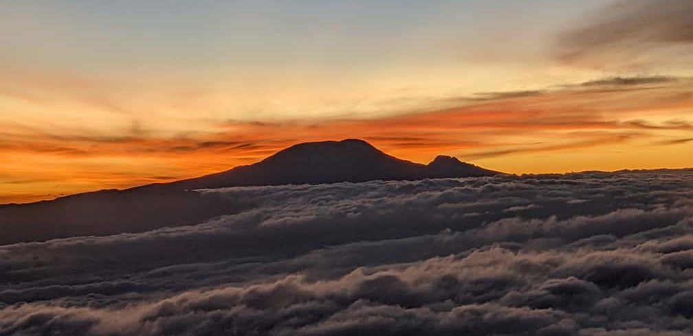 Kilimanjaro view in the distance from Mount Meru peak.